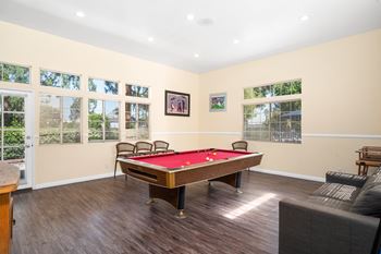 A pool table is in the middle of a room with a couch and chairs.